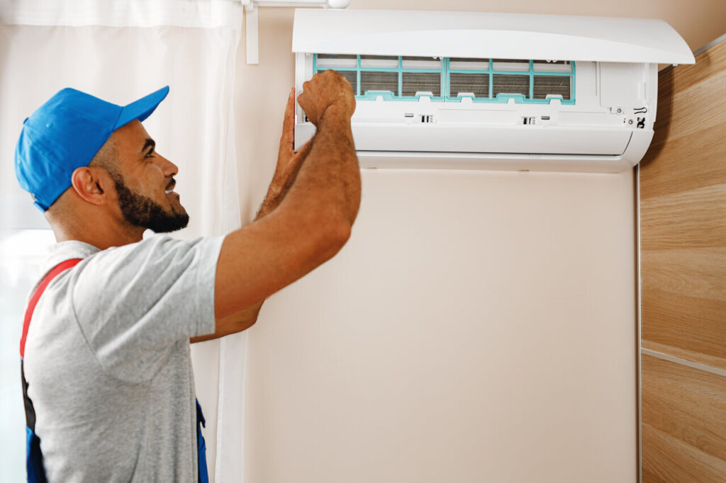 A technician is servicing an air conditioner, concentrating on repairs to enhance cooling efficiency